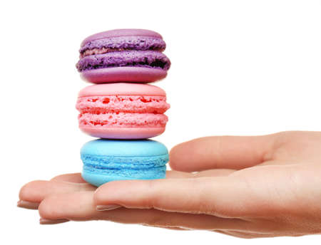 Tasty colorful macaroons in female hand isolated on whiteの写真素材