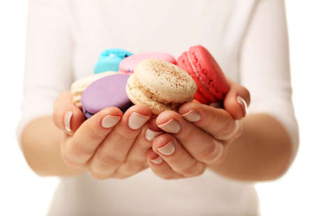 Tasty colorful macaroons in female hands on white background, closeup viewの写真素材
