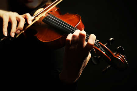 Violinist playing violin on dark backgroundの写真素材