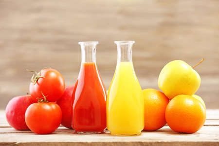 Glass bottles of fresh healthy juice with set of fruits and vegetables on wooden backgroundの写真素材