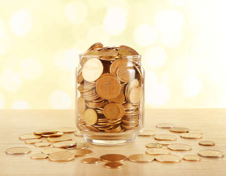 Gold coins in glass bottle on bright blurred backgroundの写真素材