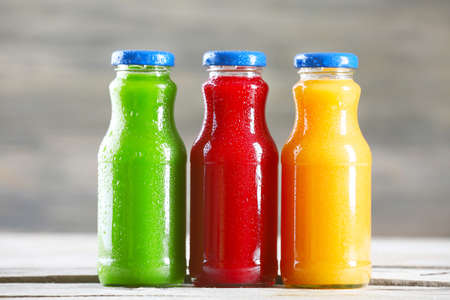 Glass bottles of fresh healthy juice on wooden backgroundの写真素材