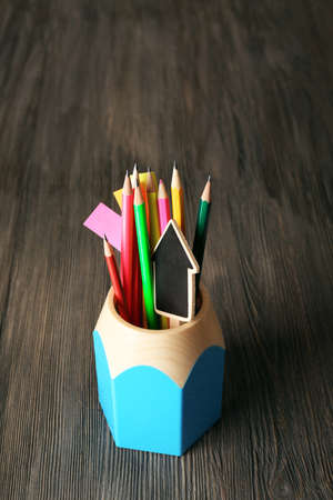 Colorful pencils with paper notes in holder on wooden table の写真素材