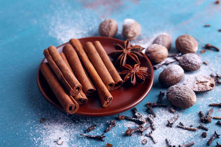Cinnamon sticks, star anise, nutmeg and cloves on color wooden table backgroundの写真素材