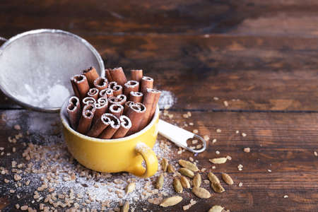 Cinnamon sticks in cup with sugar on wooden table backgroundの写真素材