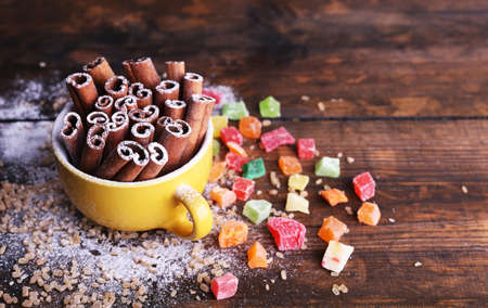 Cinnamon sticks in cup with sugar and dried fruits on wooden table の写真素材