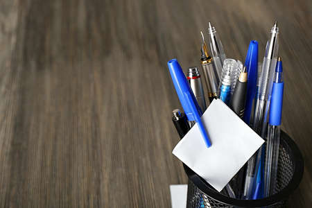 Pens in metal holder on wooden table backgroundの写真素材