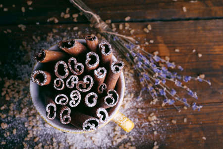 Cinnamon sticks in cup with sugar and lavender on wooden table backgroundの写真素材