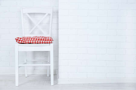 Wooden chair with pillow on white brick wall backgroundの写真素材
