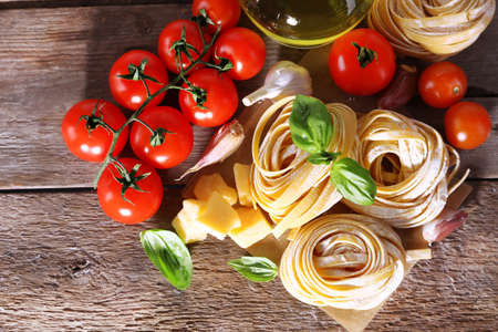 Pasta with cherry tomatoes and other ingredients on wooden table backgroundの写真素材