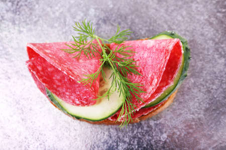 Sandwich with salami and cucumber on metal tray backgroundの写真素材
