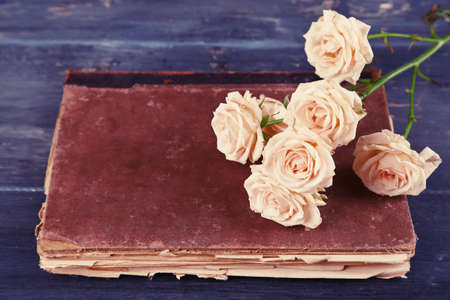 Beautiful roses with vintage book on color wooden table backgroundの写真素材