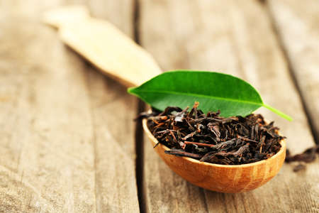 Black tea with leaf in spoon on old wooden tableの写真素材
