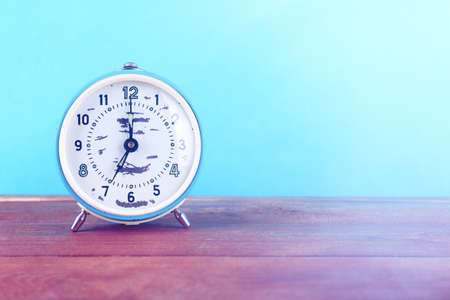 Alarm clock on wooden table on  turquoise backgroundの写真素材