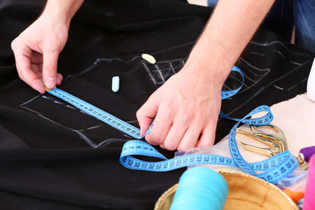 Male dressmaker drawing line on fabric on table close-upの写真素材