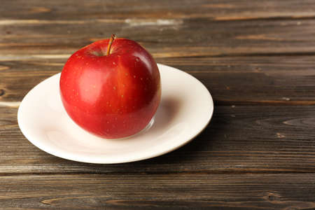 Apple on saucer on wooden backgroundの写真素材