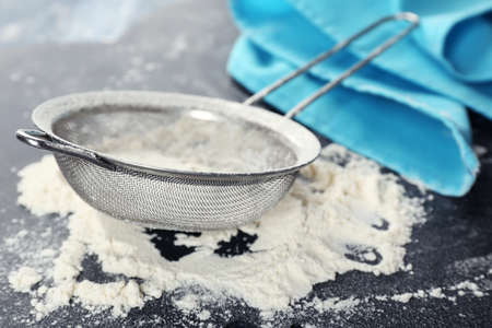 Sifting flour through sieve on wooden table, closeupの写真素材