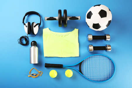 Sports equipment and T-shirt on color table, top view