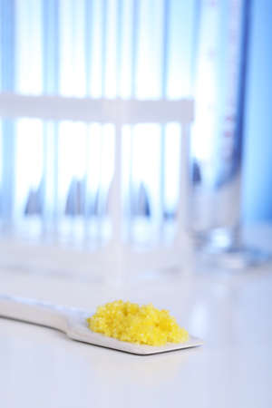 Laboratory spatula with granules on blue backgroundの写真素材