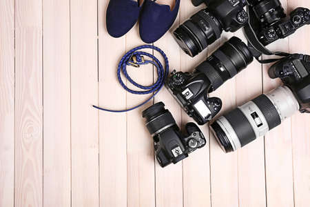 Modern cameras with female shoes and belt on wooden table, top viewの写真素材
