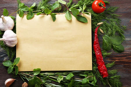 Open recipe book with fresh herbs and spices on wooden backgroundの写真素材
