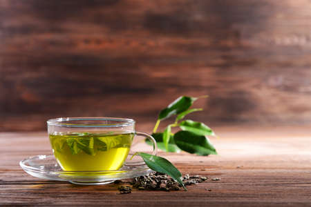 Cup of green tea on table on wooden backgroundの写真素材