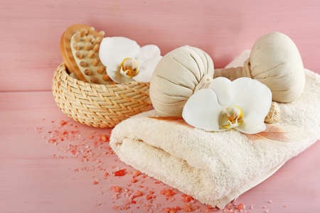 Still life with beautiful blooming orchid flower, spa treatment and pebbles, on color wooden backgroundの写真素材
