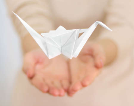 Closeup of female hands with paper craneの写真素材