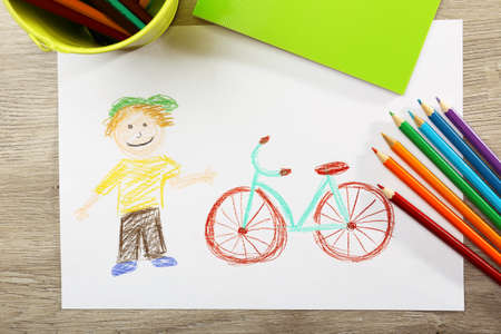 Kids drawing on white sheet of paper on wooden table, top viewの写真素材