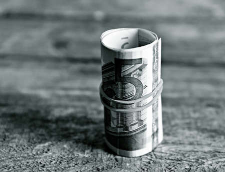 Roll of Euro banknotes on wooden backgroundの写真素材