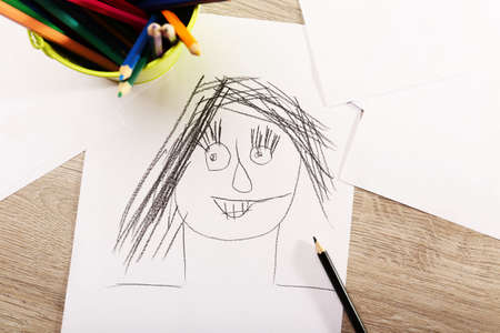 Kids drawing on white sheet of paper on wooden table, closeupの写真素材