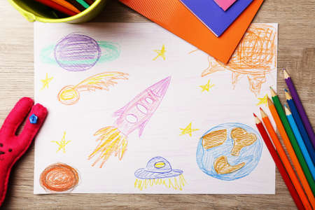 Kids drawing on white sheet of paper on wooden table, top viewの写真素材