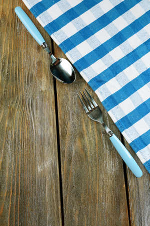 Checkered napkin with fork and spoon on wooden table backgroundの写真素材