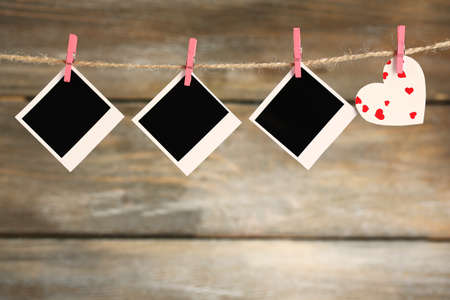 Bright heart and photo paper hanging on rope on wooden backgroundの写真素材