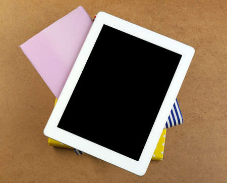 Notebook on top of pile of books and magazines on wooden backgroundの写真素材