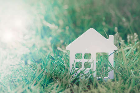 Small model of house over green grass backgroundの写真素材