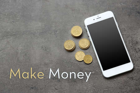 Smart phone with euro banknote and coins on grey background.の写真素材