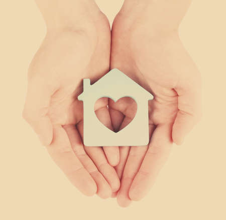 Female hands with model of house on light backgroundの写真素材