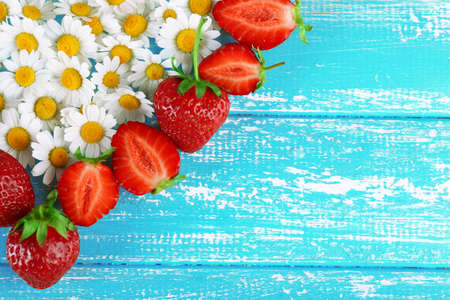 Strawberry with chamomile in shape of heart on color wooden backgroundの写真素材