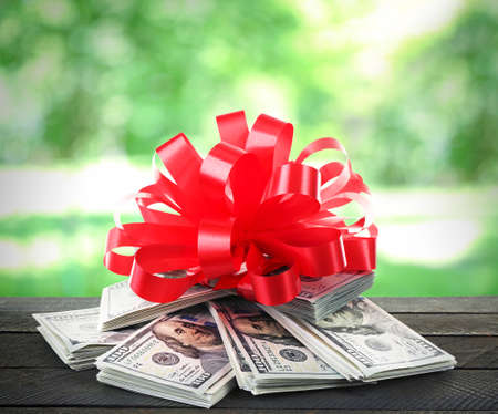 Pile of dollars with bow as gift on nature backgroundの写真素材
