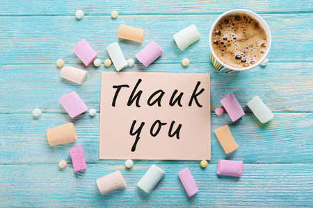 Cup of coffee with colorful pieces of chalk and note Thank You on wooden backgroundの写真素材