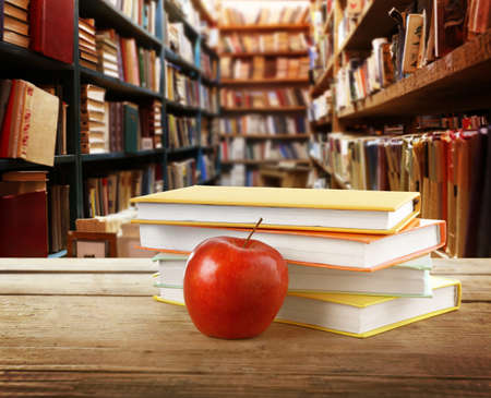Few books with red apple on blurred library backgroundの写真素材