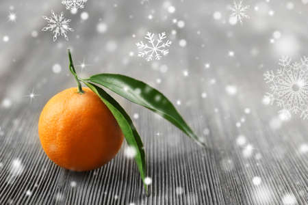 Fresh tangerines with leaves on wooden table, closeup. Snow effectの写真素材