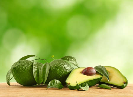 Fresh avocados on the table, on blurred nature backgroundの写真素材