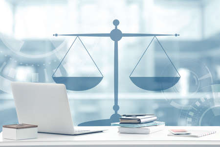Law concept. Lawyer workplace with laptop and scales of justice design on blurred background.の写真素材