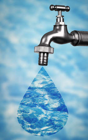 Conservation water concept. Metal faucet with drop on blurred water background.の写真素材