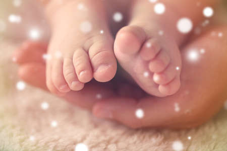 Parent hand holding baby feet, closeup. Snowy effect. Christmas and family concept.Parentの写真素材