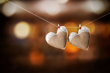 Two hearts hanging on rope against blurred background.の写真素材
