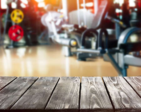 Wooden table against blurred gym interior background. Sport and healthcare concept.の写真素材