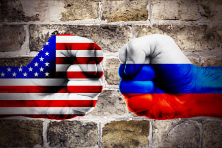 Governments conflict concept. Male fists colored in USA and Russian flags on brick wall backgroundの写真素材